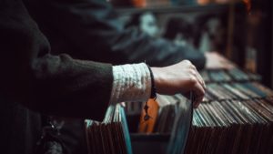 the wrist and arm of a woman sorting through a row of LP records