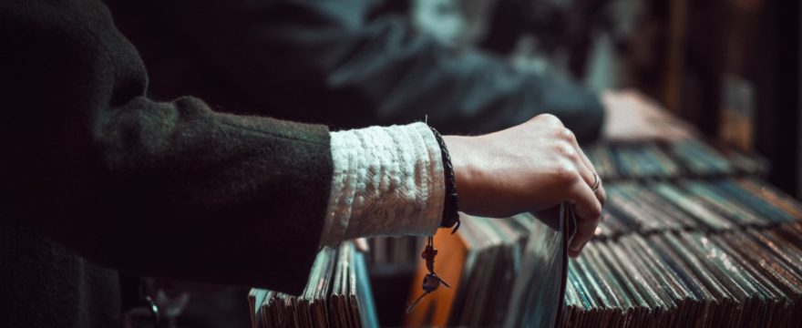 the wrist and arm of a woman sorting through a row of LP records