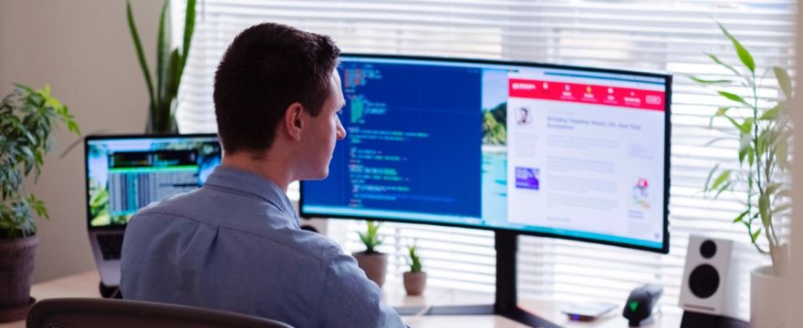 a man sitting at a desk in front of two computer monitors