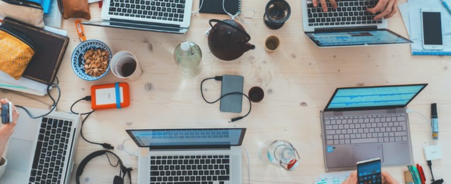 laptops notebooks and coffee cups around a table