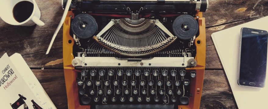 an orange typewriter on a wooden tabletop